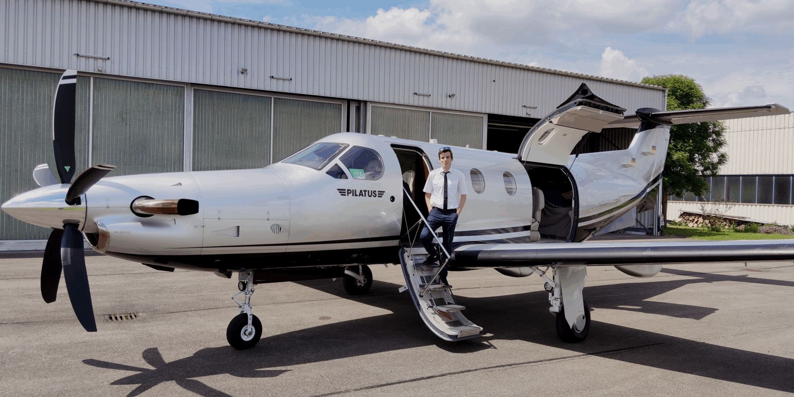 Tim Hittinger de pie en la escalerilla de un Pilatus PC-12, delante de un hangar.